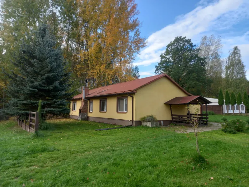 Domek 4-segmentowy z czerwonobrązowym dachem i altaną na trawniku wśród jesiennych drzew