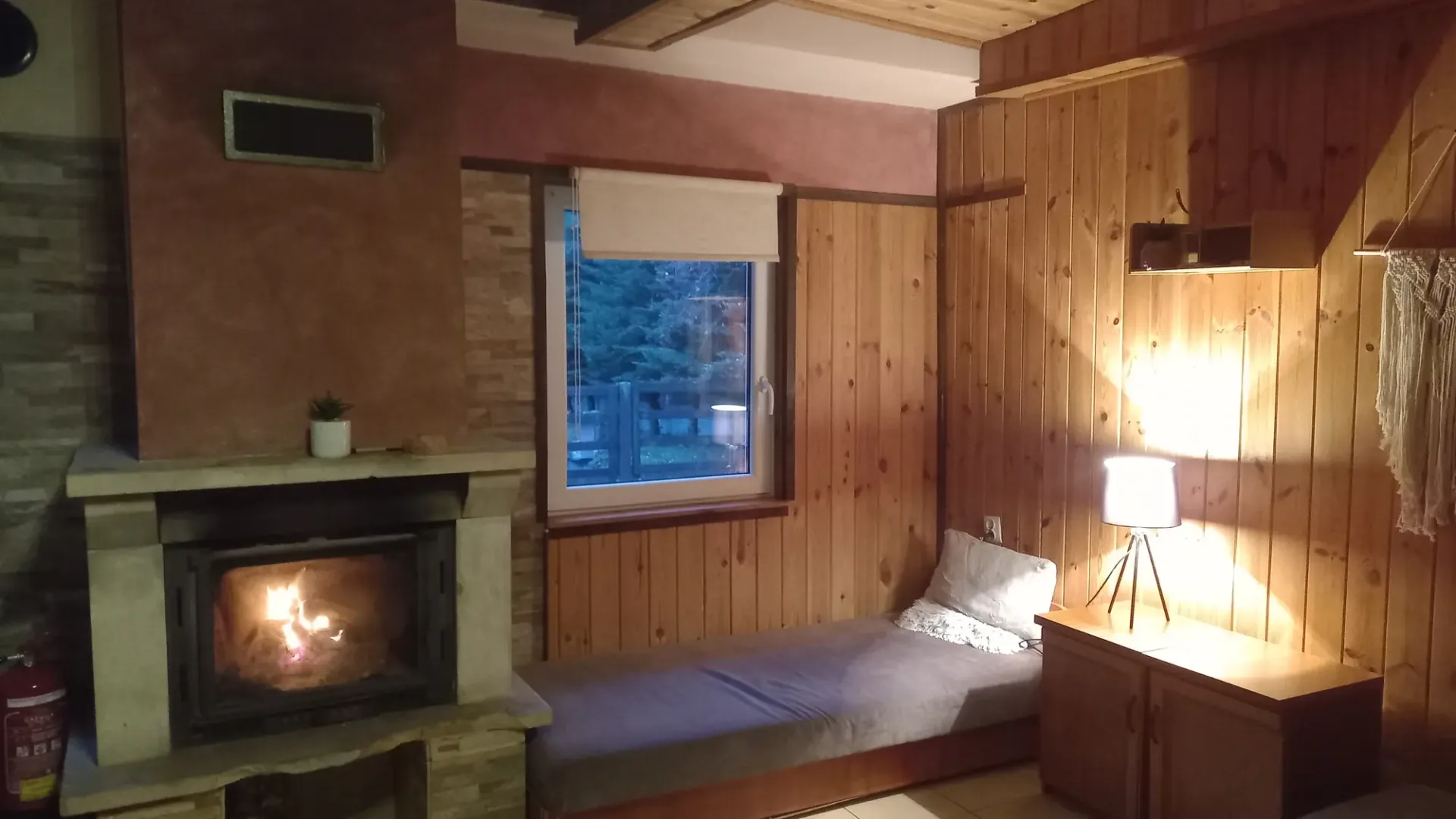 Pokój w domku nr 3 z zapalonym kominkiem i drewnianą boazerią
