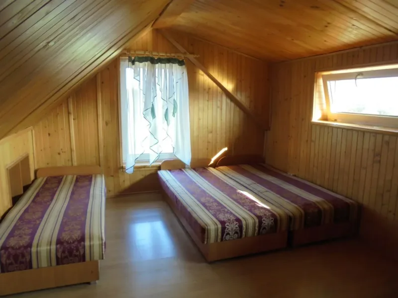 Pokój na poddaszu mini pensjonatu z drewnianą boazerią i trzema łóżkami
